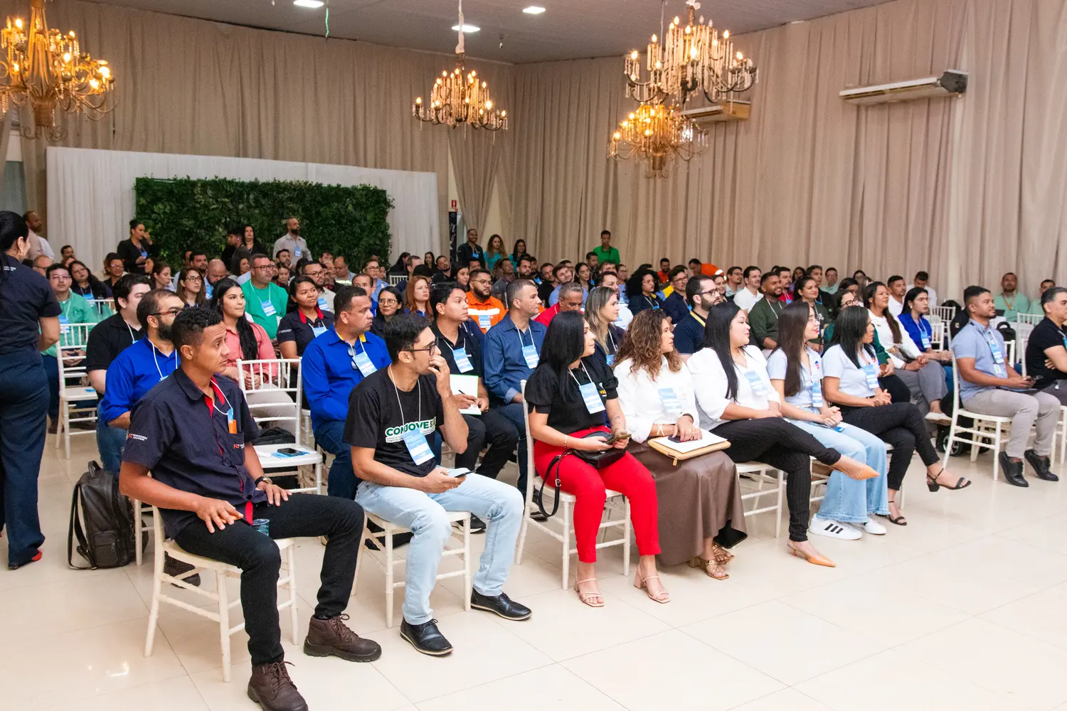 Audience seated in a hall with chandeliers at an event