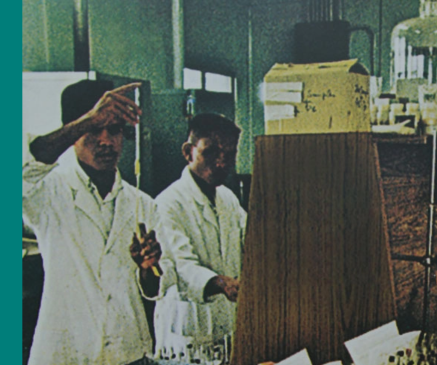 Scientist holds syringe in left hand while another watches him.