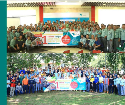 Employees hold celebration banner in front of them while posing for a photo.