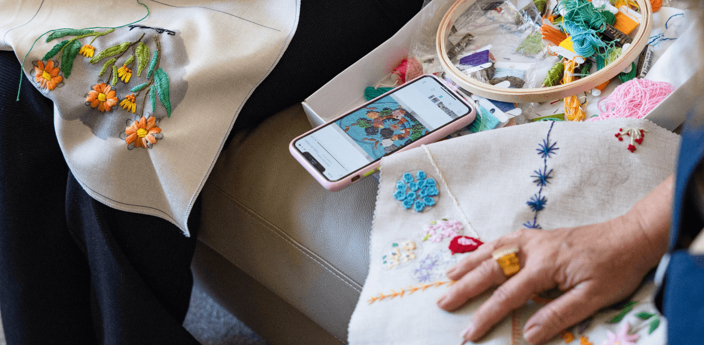 Photo of a hand under fabric embroidered with colored threads.