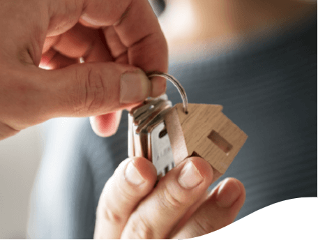Photo of a hand handing over a key holder of a house to another hand.