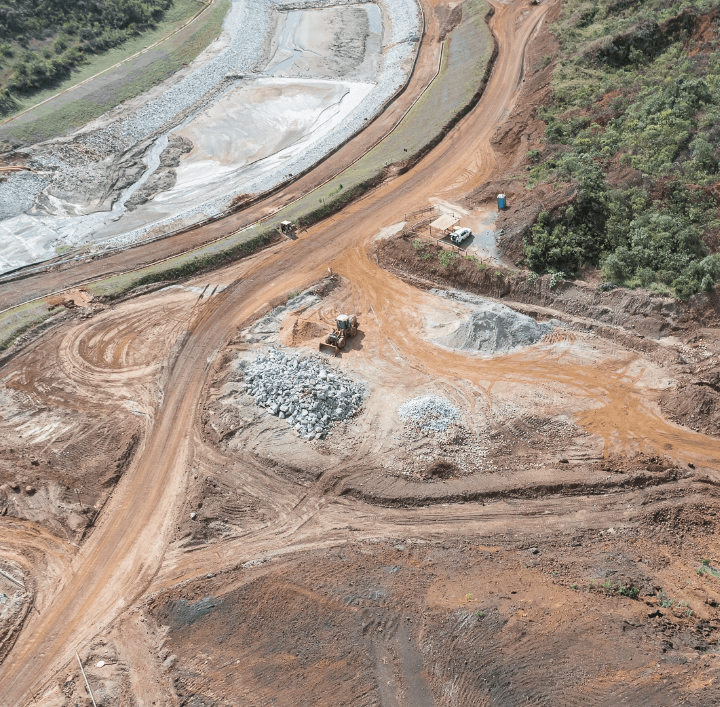 Foto de uma obra para eliminação de barragem com caminhões, terra, vegetação