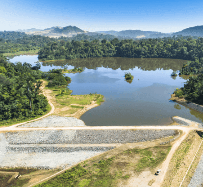 Foto de barragem eliminada com pedras, um rio, caminho de terra e vegetação ao redor