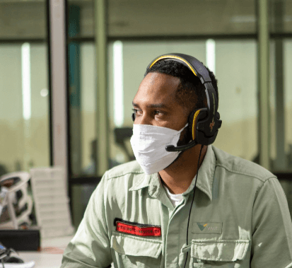Man, wearing mask and headset with microphone, inside an office.