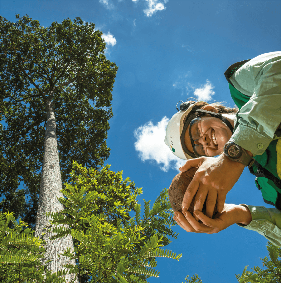 A woman holding a circular object on her hands. She is in a place with trees