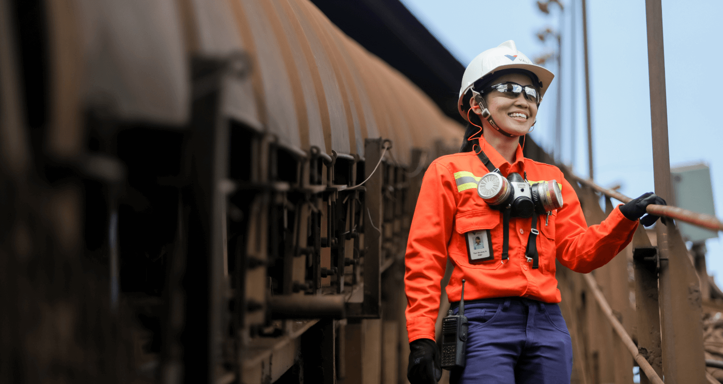 A woman wears a Vale uniform, goggles, helmet and other protective gear as she poses smiling for a photo.