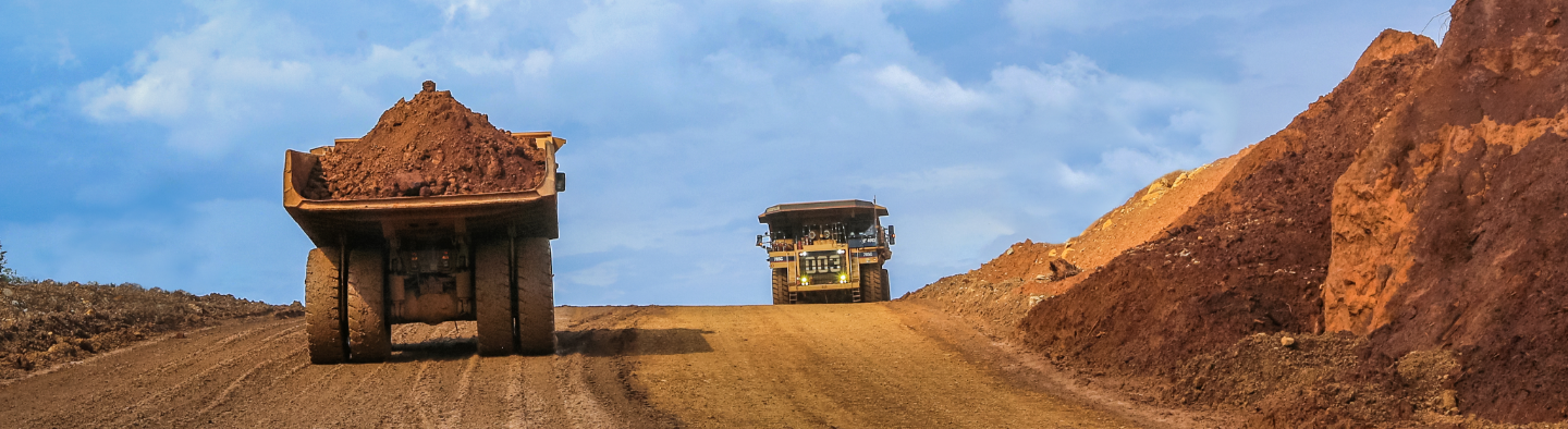 On a dirt road, a truck loads sediment