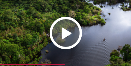 Aerial view of the river with some fishermen sailing and vegetation on the banks.