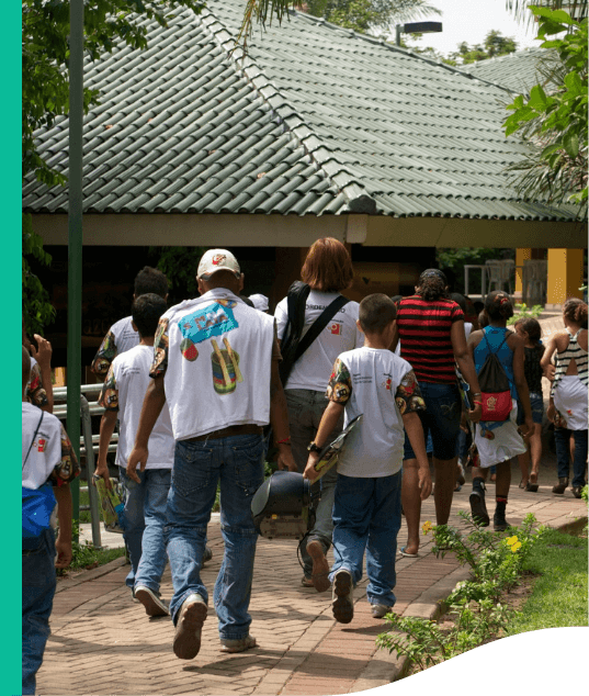 Several people are walking, all with their backs to the photo. In the background, it is possible to see the roof of a structure.