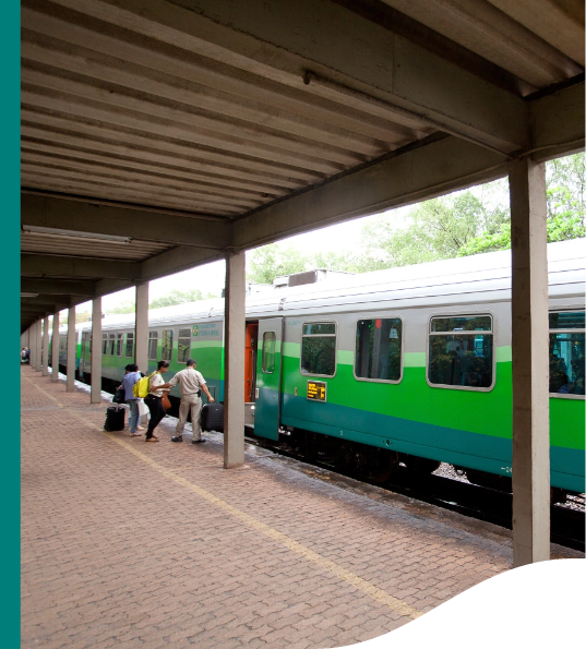 Um trem Vale está estacionado na plataforma e três pessoas, acompanhadas de malas, estão embarcando.