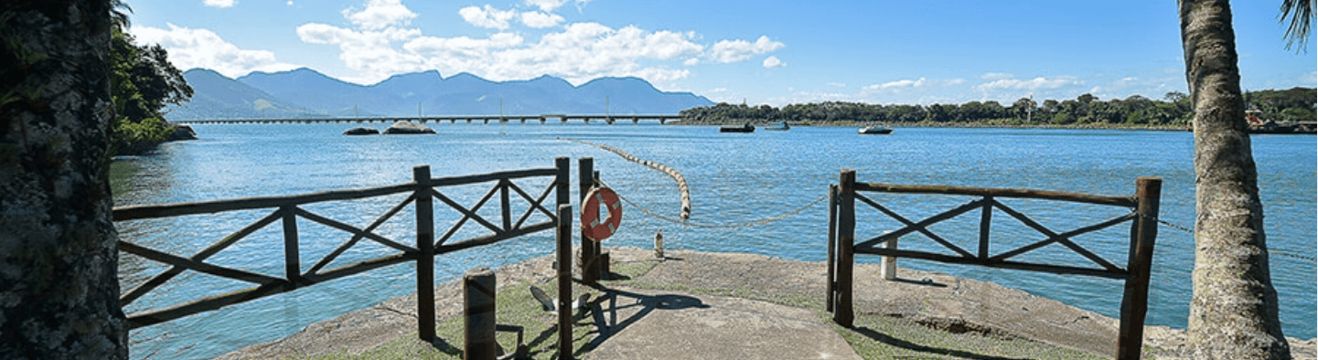 Photo of a sea and concrete part with railing and a hanging lifebuoy