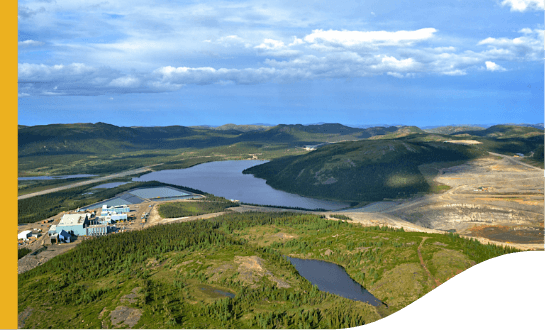 A mountainous area covered in undergrowth, with the presence of water and few buildings.