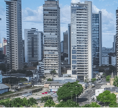 Photo of a city with several tall buildings, streets and some cranes next to a warehouse.