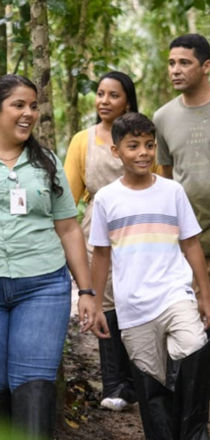 Uma empregada Vale caminha junto com uma familia por um espaço arborizado