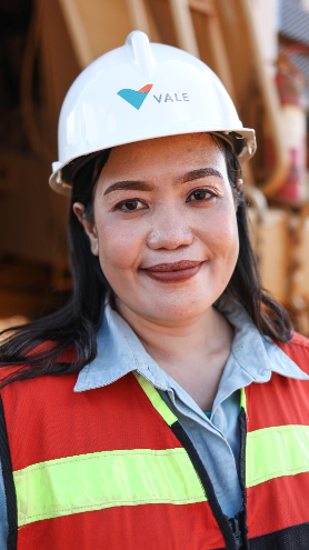 An employee wearing a helmet and reflective vest smiles sympathetically for the photo.