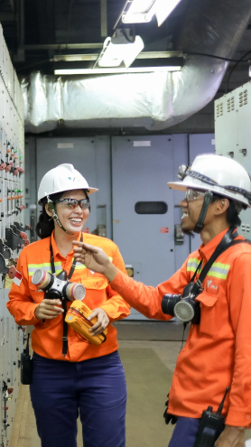 Two uniformed employees wearing protective gear smile as they chat on the premises.