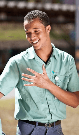 Foto tirada da cintura para cima de um empregado da Vale. Ele está sorrindo e usa uma camisa verde em um tom claro.