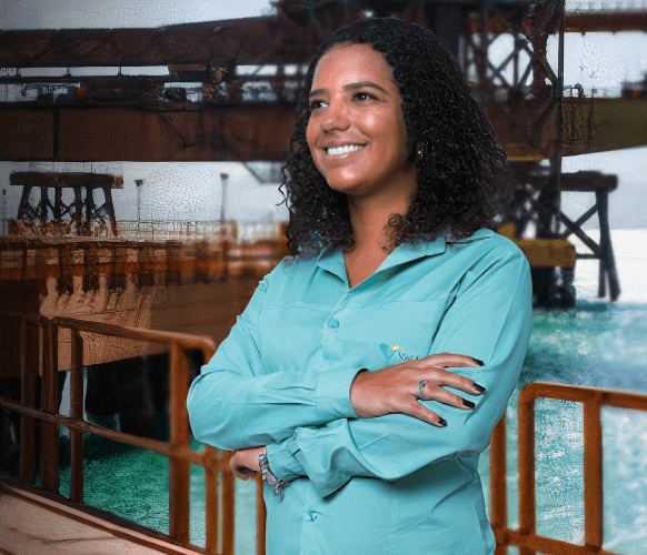 Vale female employee is with her arms crossed and smiling. In the background, it is possible to see a port operation.