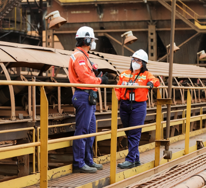 A group of Vale employees in an open area. They are wearing vests, uniforms and protective hats.