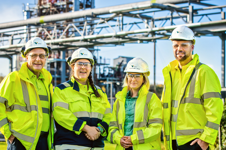 Four employees, all of them wearning Vale's uniform and protect equipaments, are in an outside area