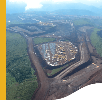 Aerial image of an outdoor operation, surrounded by vegetation. In the middle, you can see some structures, similar to sheds.