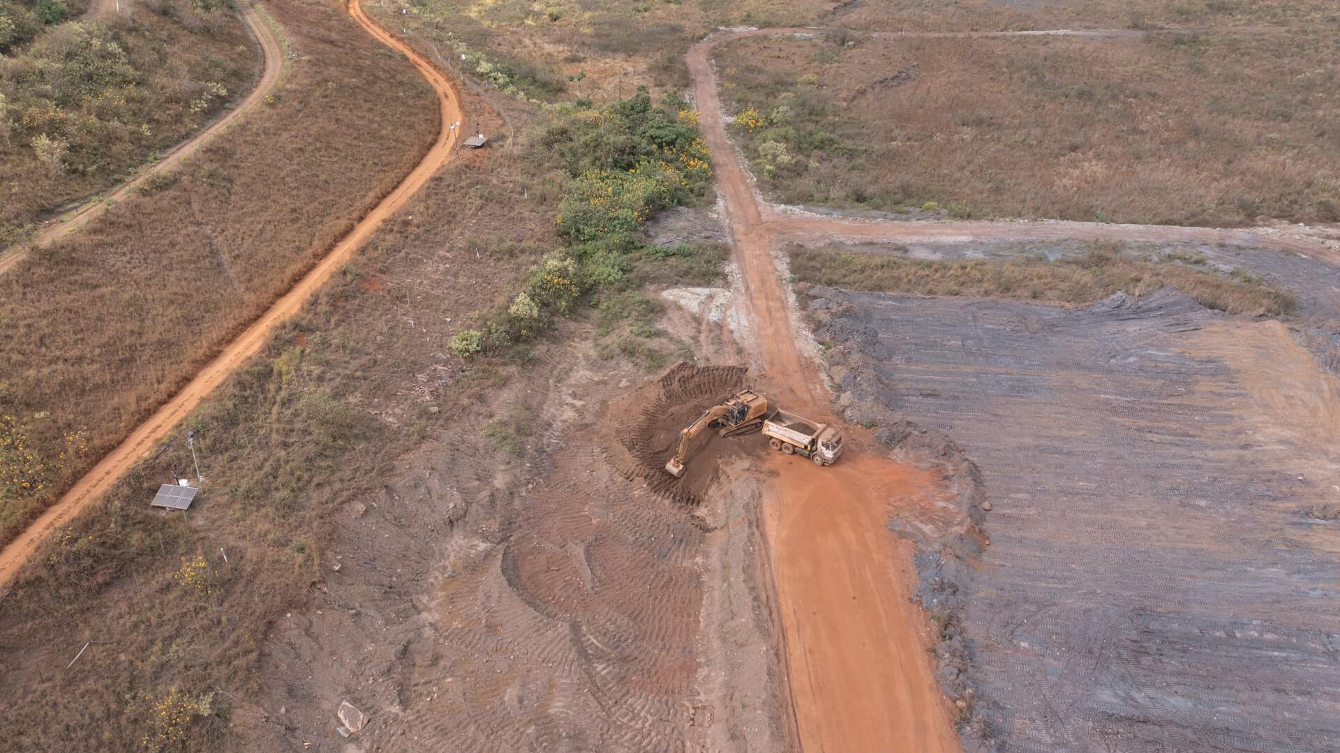 Trator e caminhão fazendo escavações em um terreno arenoso