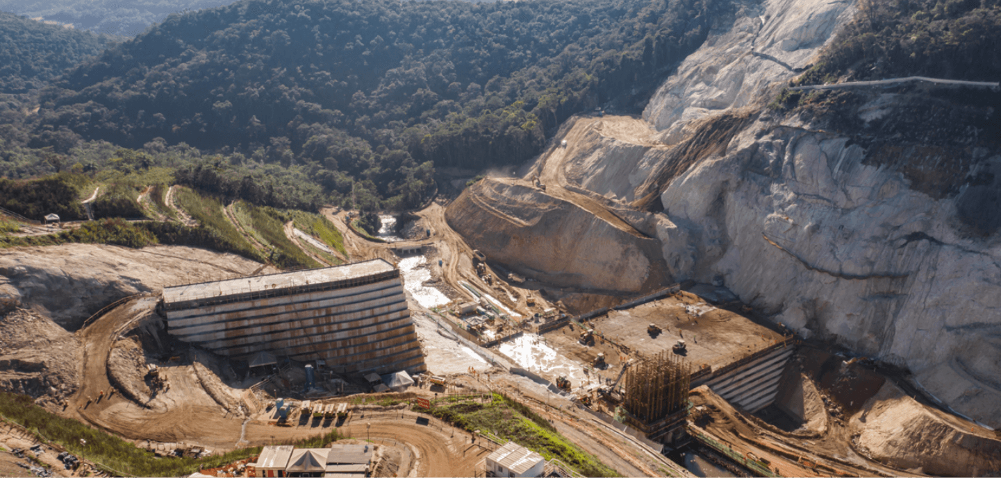 Estrutura de contenção em obra com terra, concreto e vegetação ao redor.