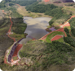 Imagem aérea da barragem Principal. Há uma área de vegetação ao redor e a área de barragem ao centro da imagem. 