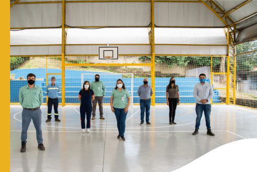 Oito pessoas, entre elas, empregados Vale, estão em uma quadra esportiva. Todos estão distantes uns dos outros e usam máscara de proteção.