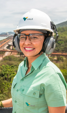 Funcionária da Vale com equipamento de segurança sorrindo para a foto.