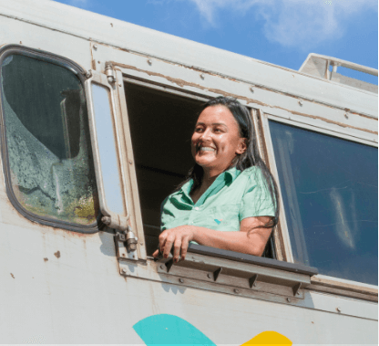 A woman smiling in the direction of one of Vale's trains. She is wearing a light green shirt.