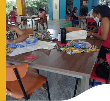 Several women are seated around tables, handling fabrics.