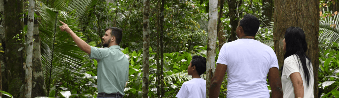 An employee is accompanied by other people along a trail in a place with a lot of trees.