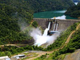 Photo of Wabageshik small hydropower plant with a concrete structure, rocks, vegetation, and moving water passing through the structures.