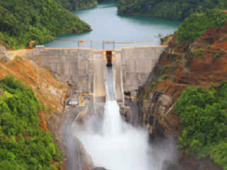 Foto da pequena central hidrelétrica Wabageshik com uma estrutura de concreto, pedras, vegetação e água em movimento passando pelas estruturas.
