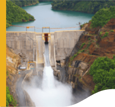 Photo of Wabageshik small hydropower plant with a concrete structure, rocks, vegetation, and moving water passing through the structures.