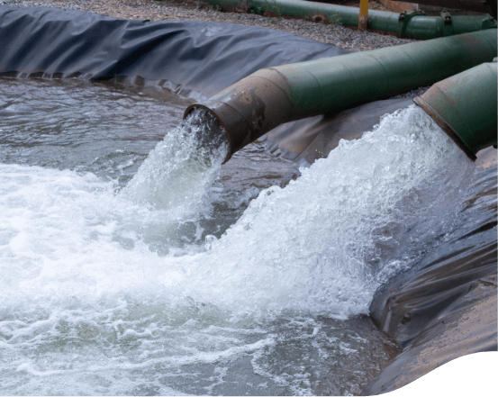 Two pipes are pouring high amounts of water into a space lined with black tarp.